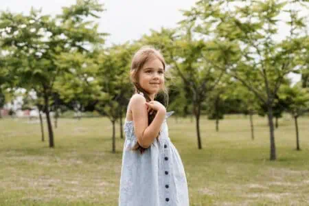 Cheerful girl in dress walking in the park