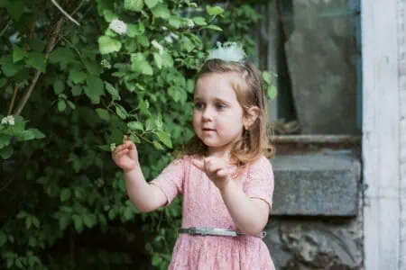 Little cute girl in pink dress having fun in the garden