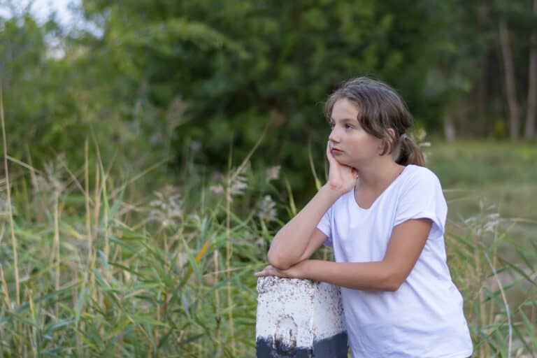 Beautiful girl in white clothes in the meadow looking to the side