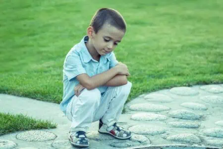 Little boy looking sad while sitting outdoors
