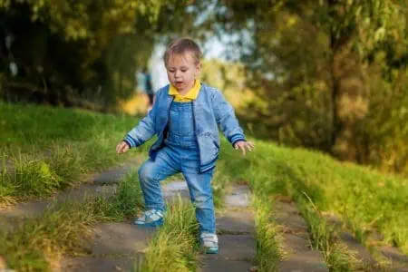 Little boy in denim goes down the stairs in the public park