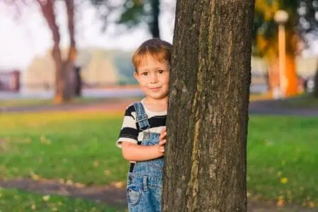 Cute little boy standing by the tree in the park