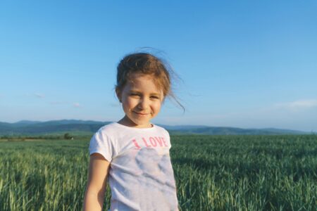 Smiling young girl in green grass field at sunset