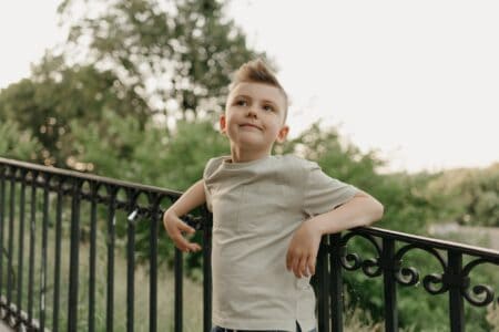 Adorable young boy leaning against the iron stair railing at the park