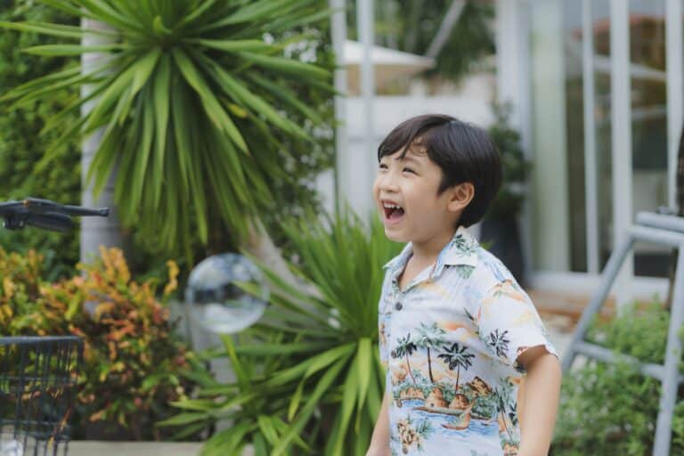 Asian boy having fun with soap bubble at park