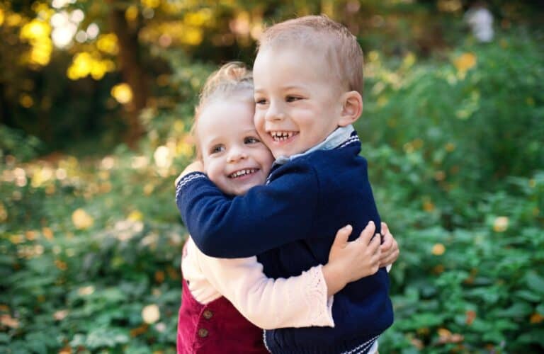 Adorable boy and girl hugging each other in autumn forest