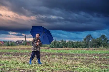 Young boy holding an umbrella under stormy clouds