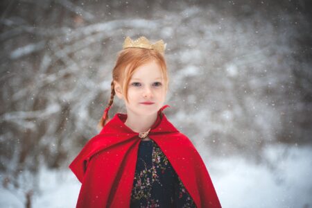 Girl in red coat with a gold crown on her head