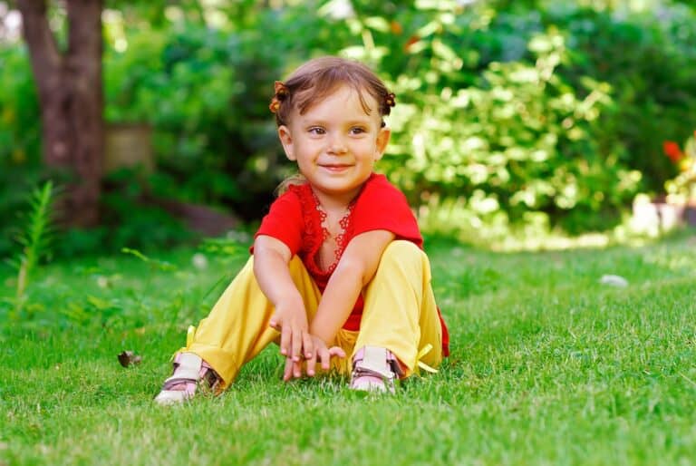 Beautiful little girl sitting on green lawn