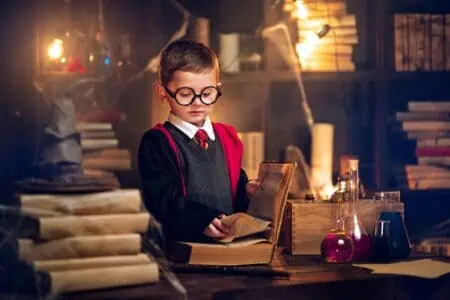 Little young boy cosplaying harry potter reads magic book