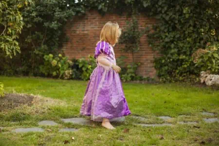 Queen little girl wearing gown and crown having fun in the garden