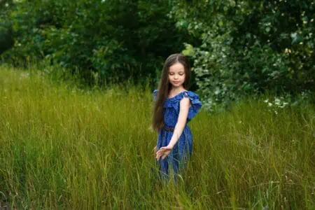 Pretty little girl in blue dress relaxing in the meadow